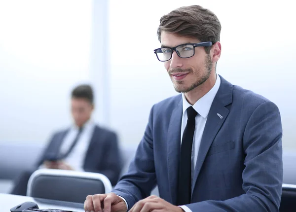 Empresário usando um laptop, olhando para a câmera e sorrindo — Fotografia de Stock