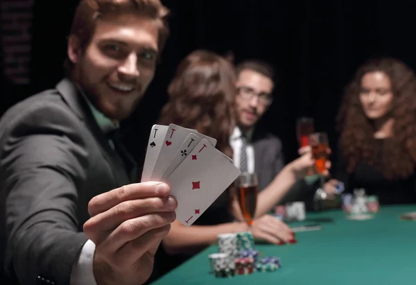 Muž hráč v kasinu, sedí u stolu s poker čipy a karty — Stock fotografie