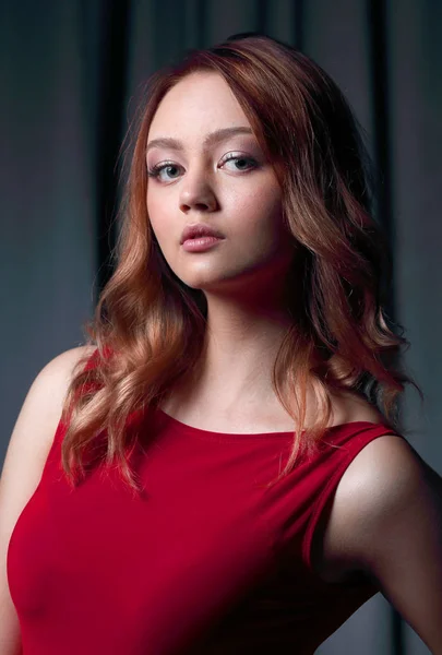 Morena encantadora em um vestido vermelho posando em um fundo preto . — Fotografia de Stock