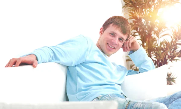 Изображение молодого человека, сидящего на диване и смотрящего в камеру — стоковое фото