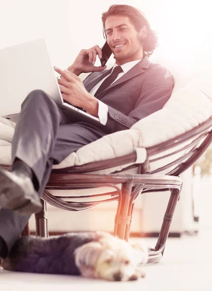 Empresário falando no smartphone sentado na cadeira em sua casa — Fotografia de Stock