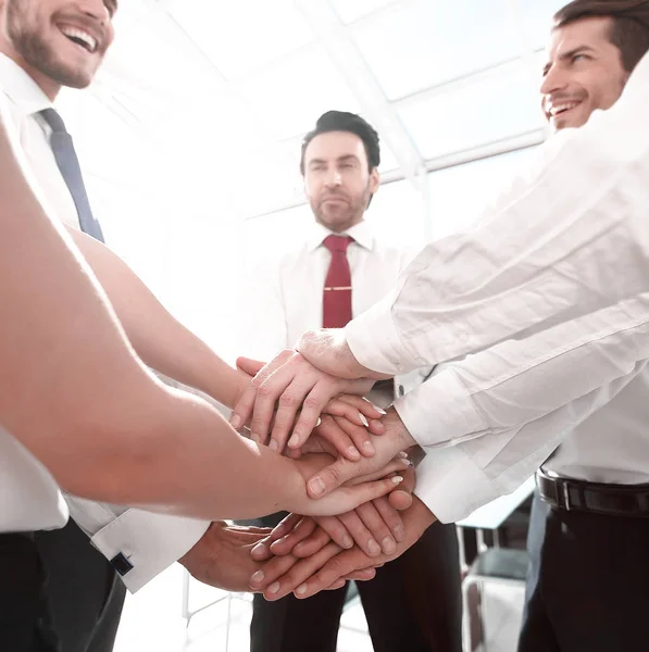 Fechar up.sorrindo equipe de negócios com as mãos dobradas junto — Fotografia de Stock