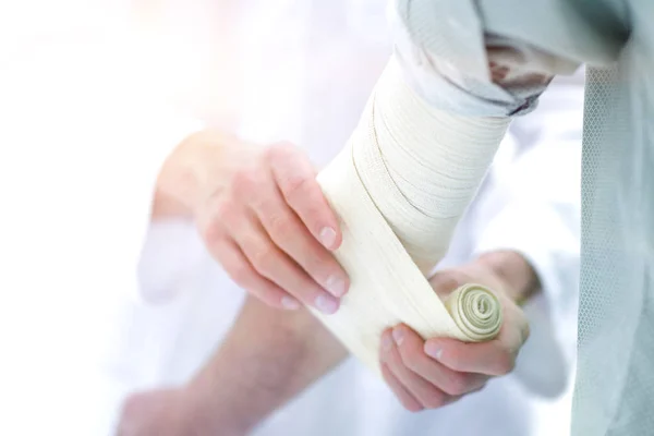 Médico aplicando bandagem elástica no cotovelo do paciente . — Fotografia de Stock
