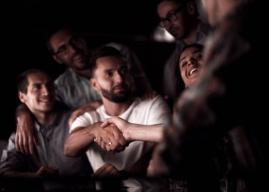 Ofis masasında el sıkışmaktan mutlu çalışanlar.