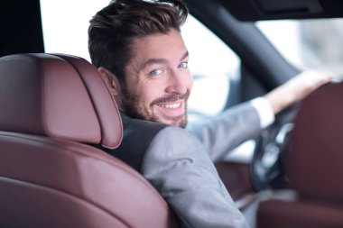 Dikiz aynası, genç adam arabasını sürüyor, kameraya bakıyor.