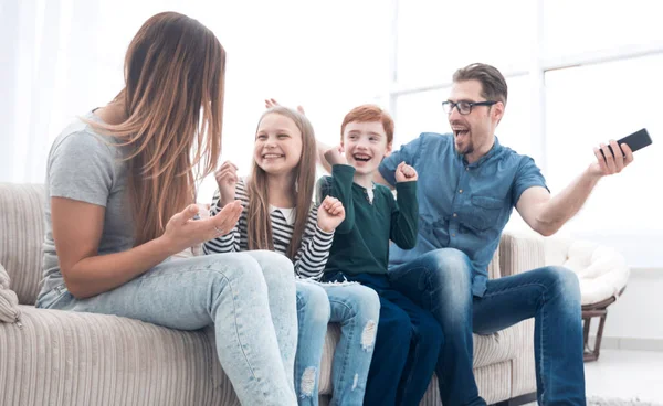 Glückliche Familie sitzt vor dem Fernseher in ihrem Haus — Stockfoto