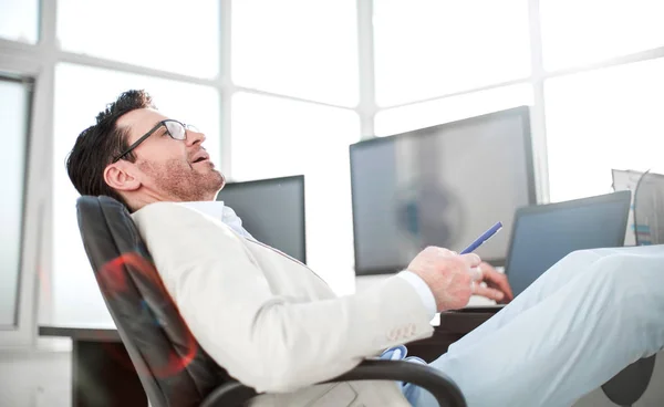 Empresário sentado em sua mesa durante uma pausa de trabalho — Fotografia de Stock