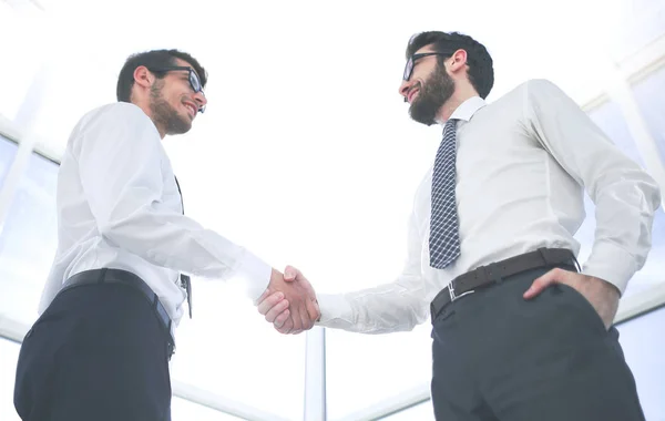 Inferior view.handshake socios de negocios de pie en la oficina —  Fotos de Stock