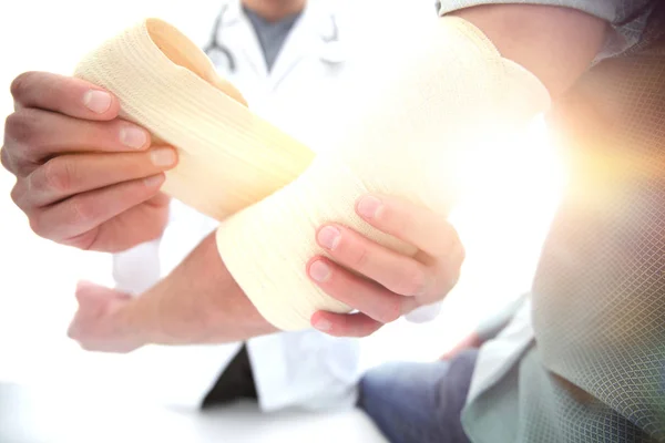 Orthopedist applying bandage onto patients hand in clinic — Stock Photo, Image