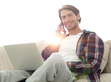 cep telefonu üzerinde konuşurken laptop ile ciddi genç adam