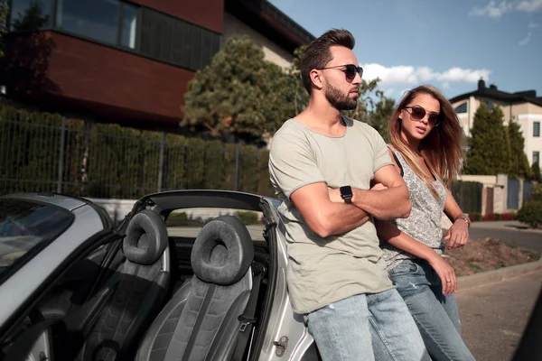 Jong koppel staande in de buurt van luxeauto. — Stockfoto