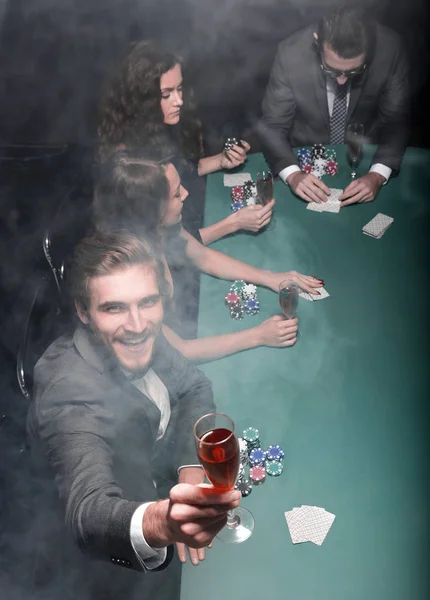 Poker player raising a glass of wine — Stock Photo, Image