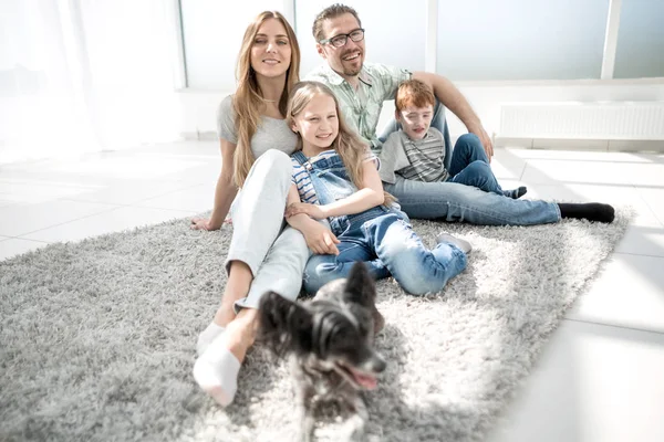 Retrato de uma família feliz sentado no chão da sala de estar — Fotografia de Stock