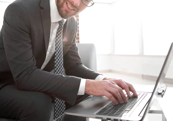 Pomyślny młody biznesmen piszący na laptopie w miejscu pracy — Zdjęcie stockowe