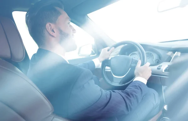 Businessman sits at the wheel in his car and looks at the road — Stock Photo, Image