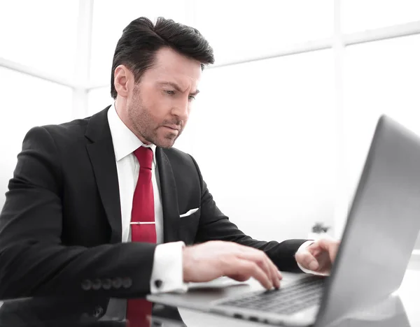 Uomo d'affari che digita su un portatile, seduto alla sua scrivania — Foto Stock