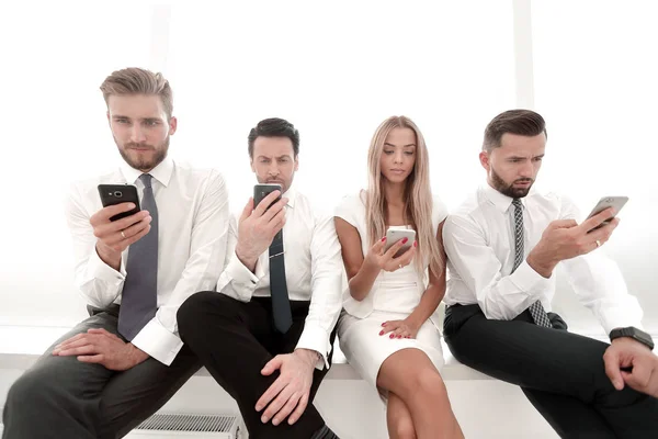 Close up.Business pessoas usando smartphones sentados em uma fileira — Fotografia de Stock