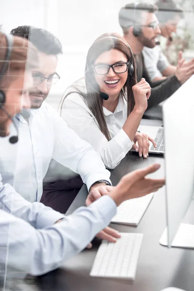 Funcionários sorridentes do call center conversam sentados atrás de uma mesa — Fotografia de Stock
