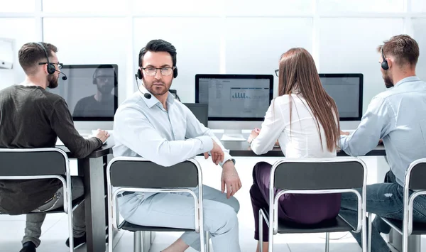 Bakre view.business man med ett headset och hans kollegor som sitter på kontoret — Stockfoto