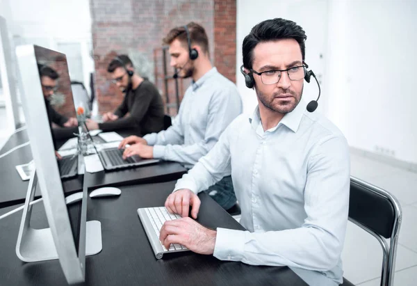 Hombre de negocios serio en un auricular sentado en un escritorio —  Fotos de Stock