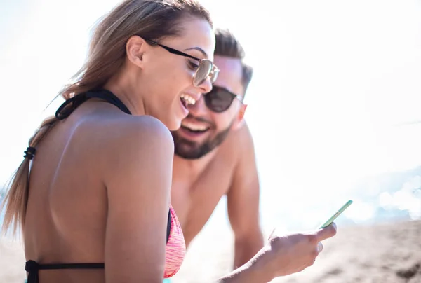 Усміхнена пара переглядає свої фотографії на пляжі — стокове фото