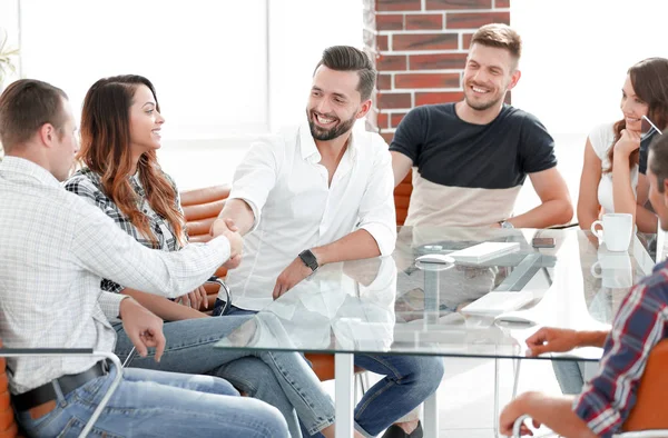 Apretón de manos de los socios comerciales sentados a la mesa — Foto de Stock