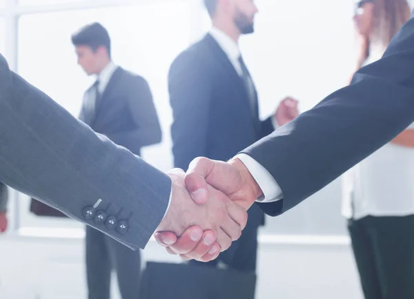 Stäng up.handshake business partners i bakgrunden av den av — Stockfoto