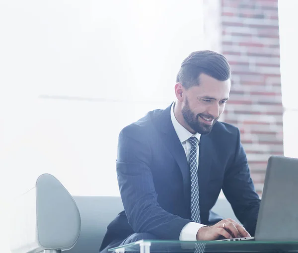 Homme d'affaires travaillant sur un ordinateur portable assis sur un canapé dans un bureau — Photo