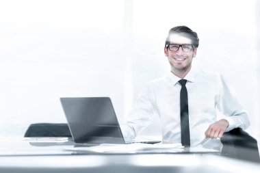 geniş bir ofiste oturan gülümseyen genç işadamı