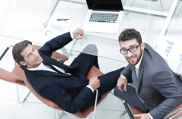 Sonrientes colegas de negocios sentados en Desk — Foto de Stock