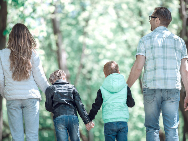 Rear view. family with two children walking hand in hand in the Park. Royalty Free Stock Photos