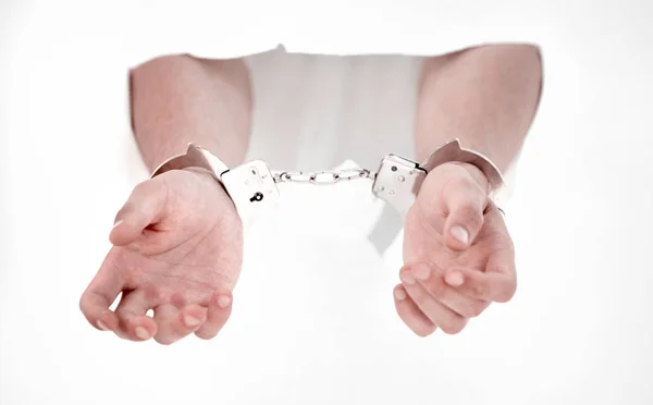 Handcuffs on the hands of a man breaking a paper wall — Stock Photo, Image