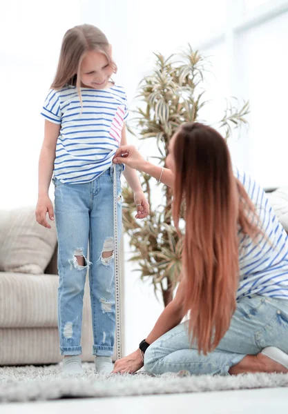 Mãe verifica o comprimento de suas filhas jeans — Fotografia de Stock