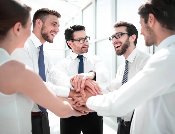 Close up.a equipe de negócios sorrindo fica com as mãos dobradas juntas. — Fotografia de Stock