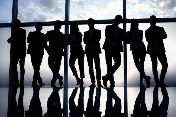 Gruppo di giovani uomini d'affari felici in piedi vicino a una grande finestra dell'ufficio — Foto Stock