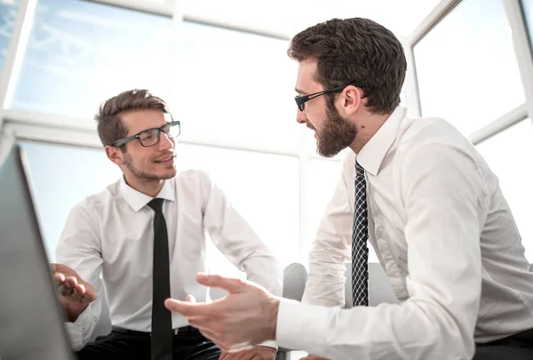 Werknemers bespreken iets zit van een opengeklapte laptop. — Stockfoto