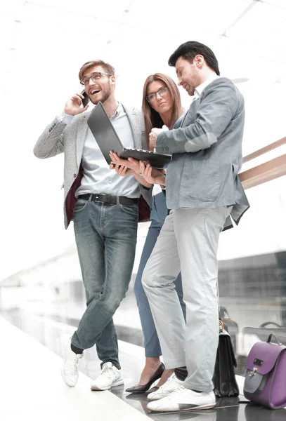 Business colleagues using their gadgets standing in the office lobby — Stock Photo, Image