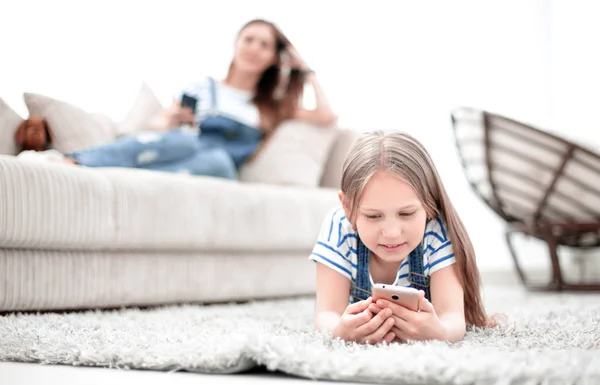 background image.mom and her daughter using their smartphones in their home