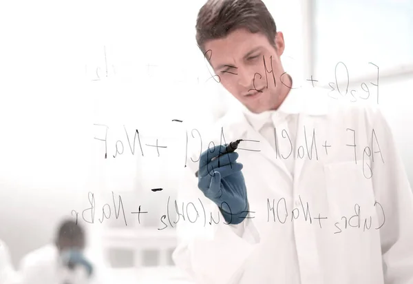 Serious scientist writes a formula on a glass Board — Stock Photo, Image