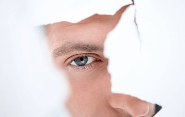 Kağıt duvardaki delikten bakan dikkatli bir işadamı..