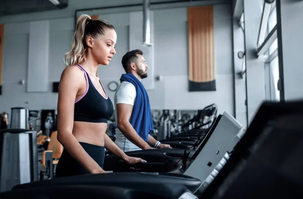 Hermosos deportistas trabajan en la cinta de correr en el gimnasio — Foto de Stock