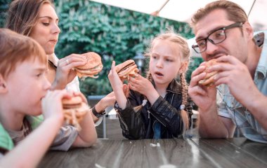 mutlu aile bir kafede bir masada oturan hamburger yemek