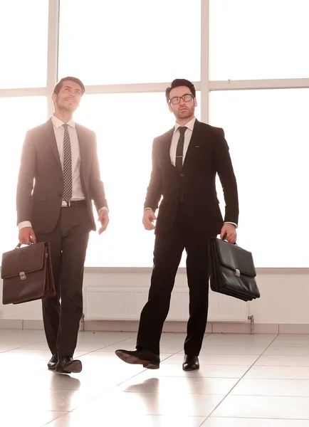 Muito longe. dois homens de negócios estão andando no lobby do escritório — Fotografia de Stock