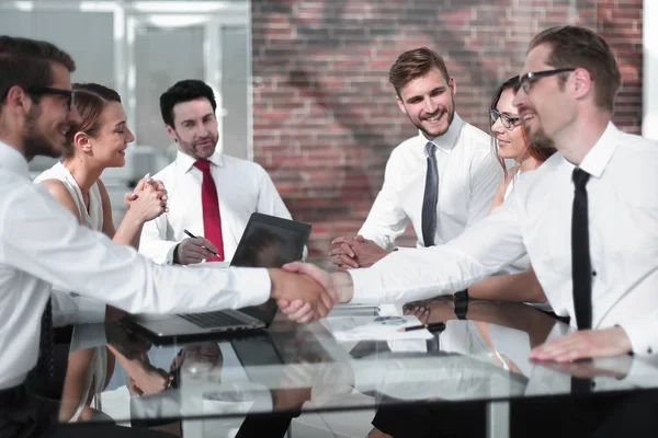 Leende affärspartners som skakar hand vid förhandlingsbordet — Stockfoto