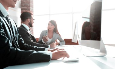 Ofis çalışanları çalışma masasında oturuyorlar.