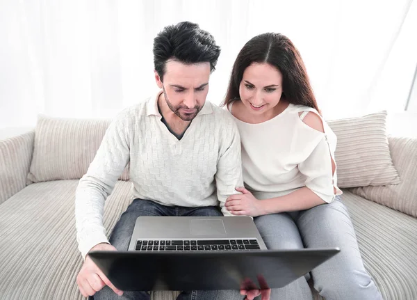 Casal com laptop sentado na sala de estar no sofá — Fotografia de Stock