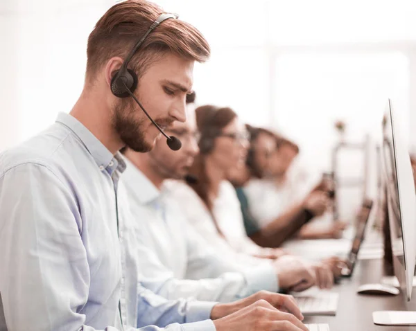 Homem bonito com um fone de ouvido trabalhando em um call center — Fotografia de Stock