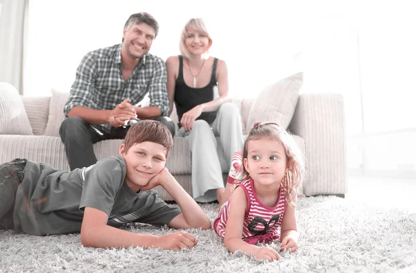Retrato de crianças enquanto os pais sentados no sofá na sala de estar — Fotografia de Stock