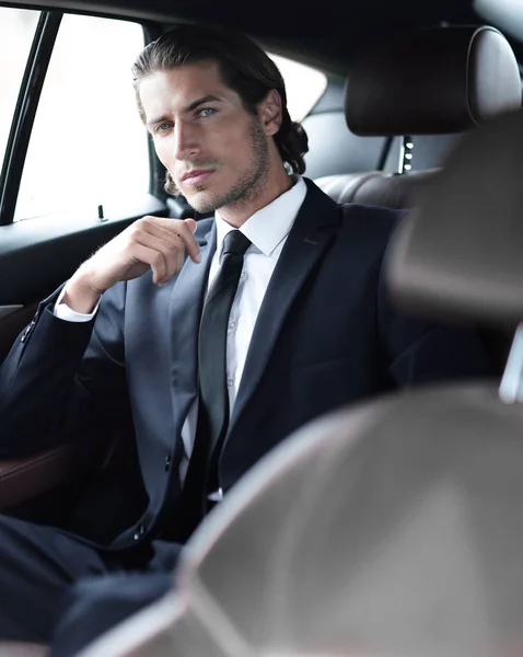 Erfolgreicher Mann sitzt auf dem Rücksitz eines Autos — Stockfoto