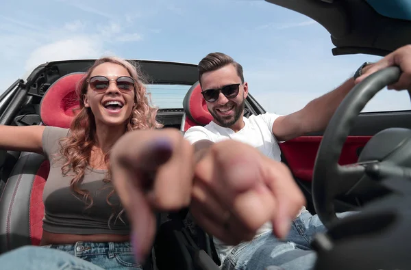 Sluit up.happy paar naar je wijzen en zitten in de auto. — Stockfoto